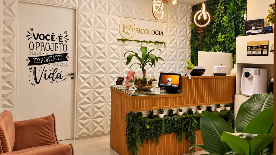 Recepção da LT Psicologia no JK Shopping, com balcão amadeirado, marca na parede e jardim vertical